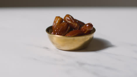 Close-Up-Of-Bowl-Of-Dates-On-Marble-Surface-Celebrating-Muslim-Festival-Of-Eid